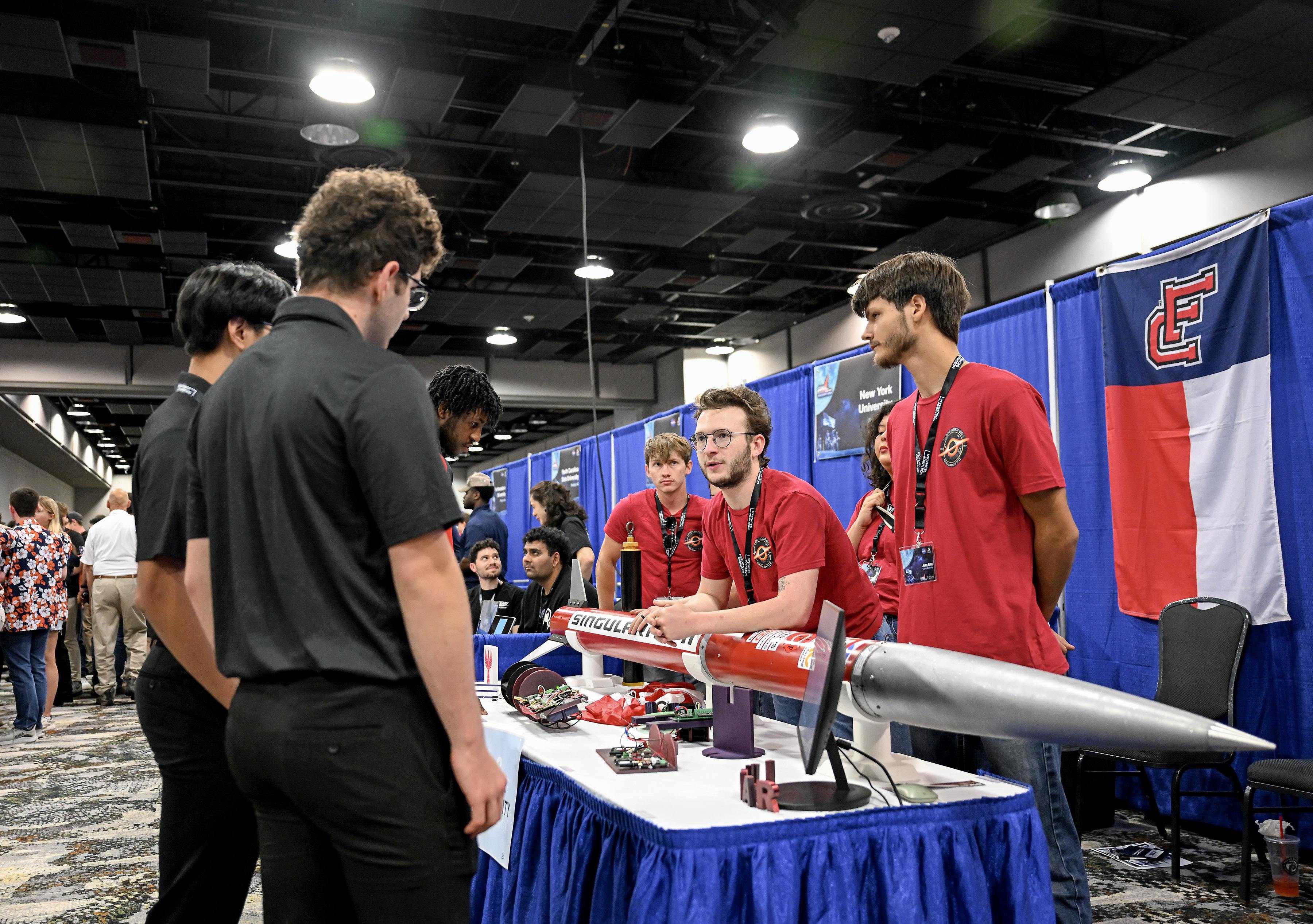LUNAR members presenting a rocket and project hardware at an outreach booth.