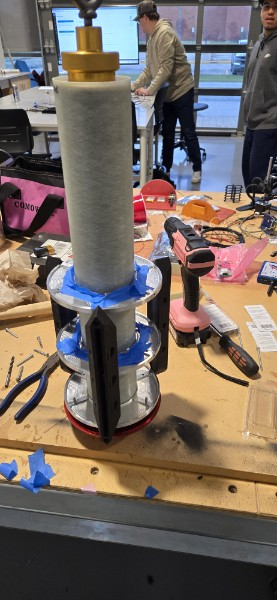 Rocket airframe hardware secured on a workbench during assembly.