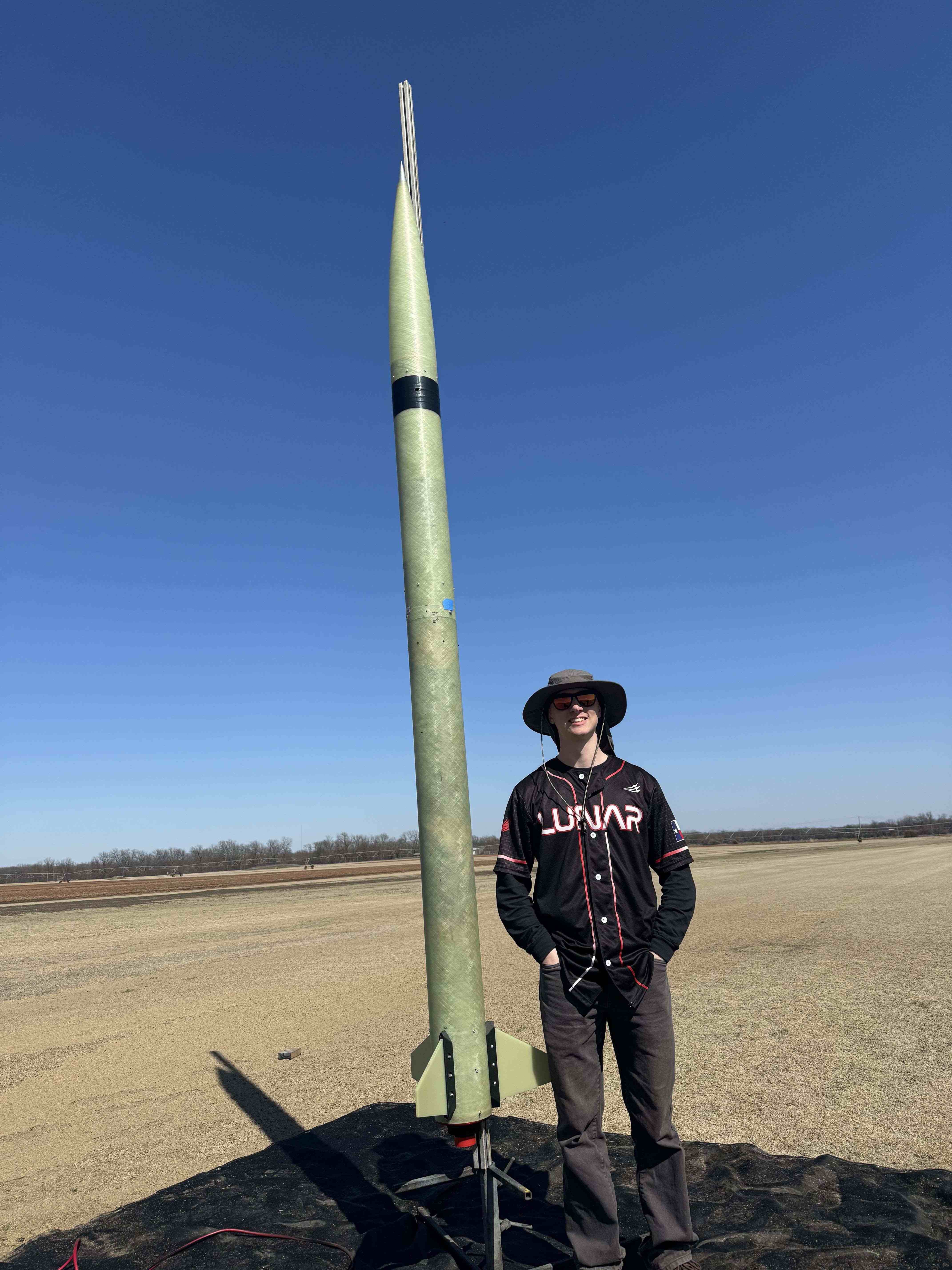 A LUNAR member standing beside a completed rocket at the launch field.